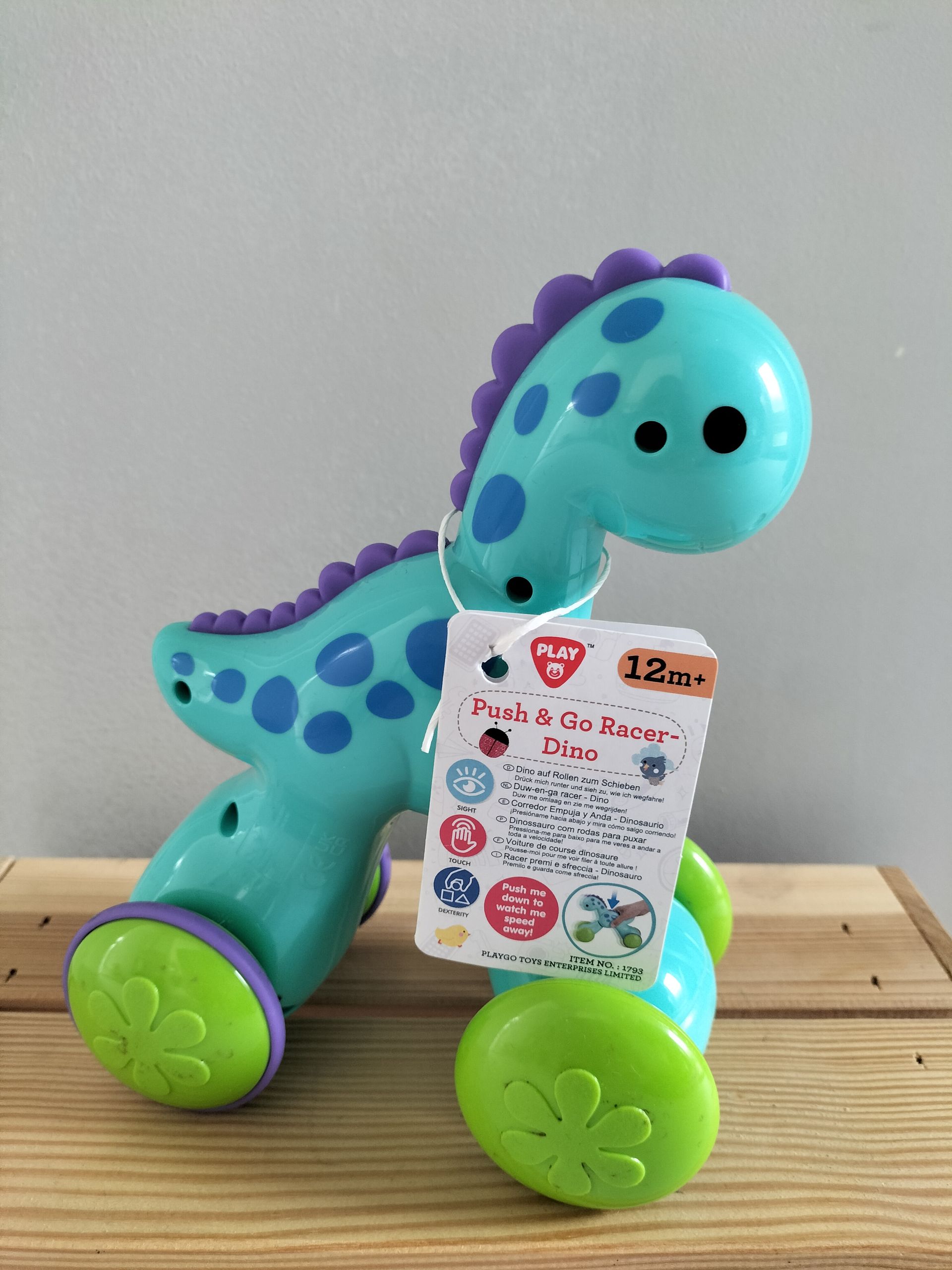 Push & Go Racer Dino. Een turquoise en paarse dinosaurus met groene wielen.