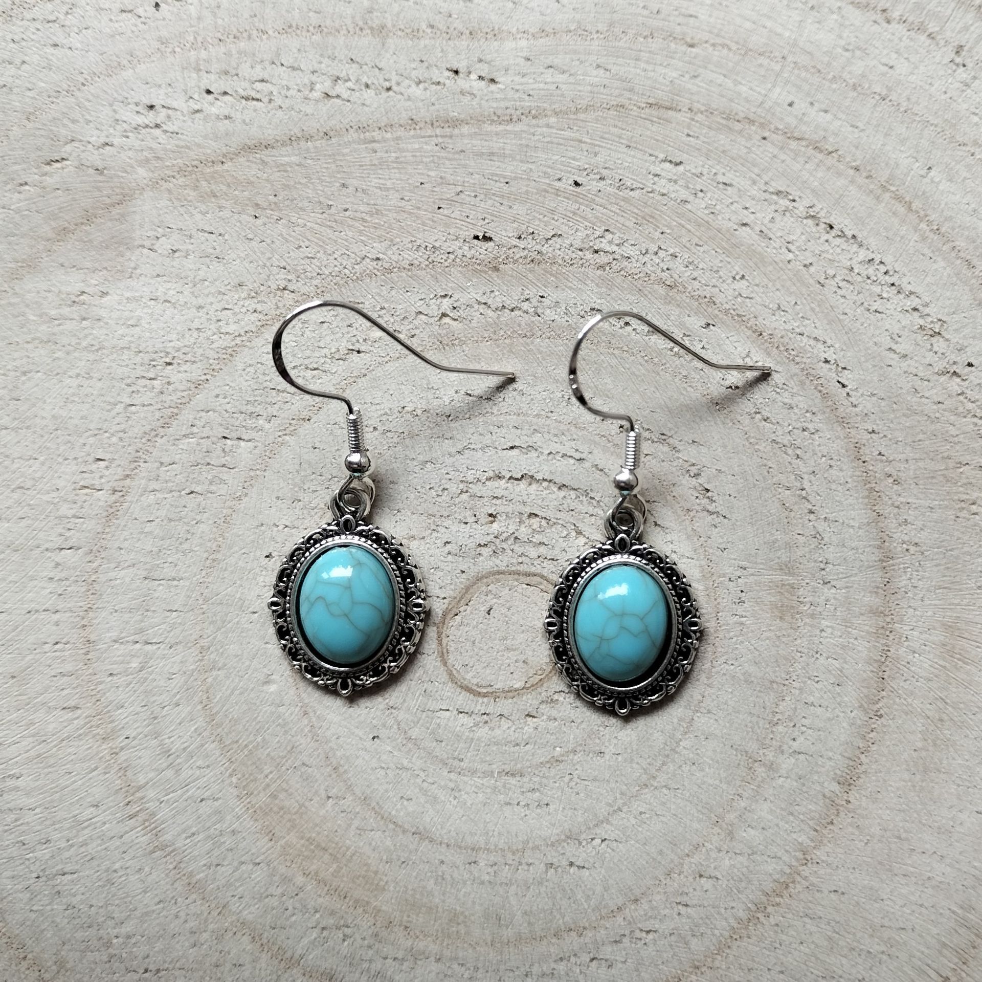 Zilverkleurige klassieke ovaalvormige oorbellen met turquoise steentje en zilveren oorhaakje.