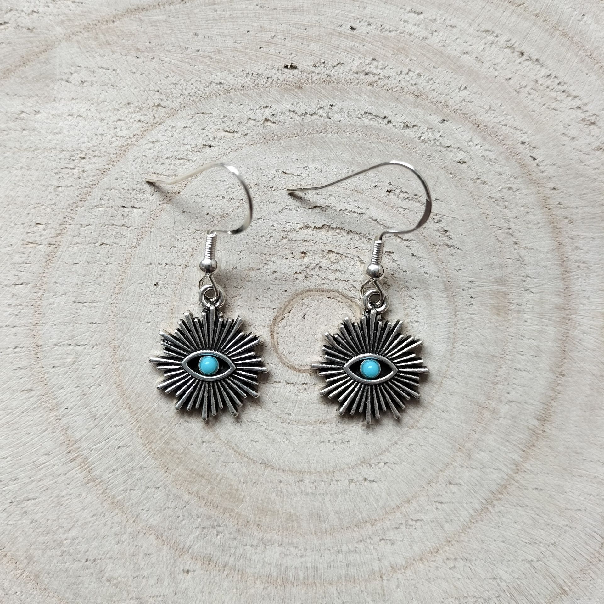 Zilverkleurige oorbellen met zonneoog en turquoise steentje en zilveren oorhaakje.