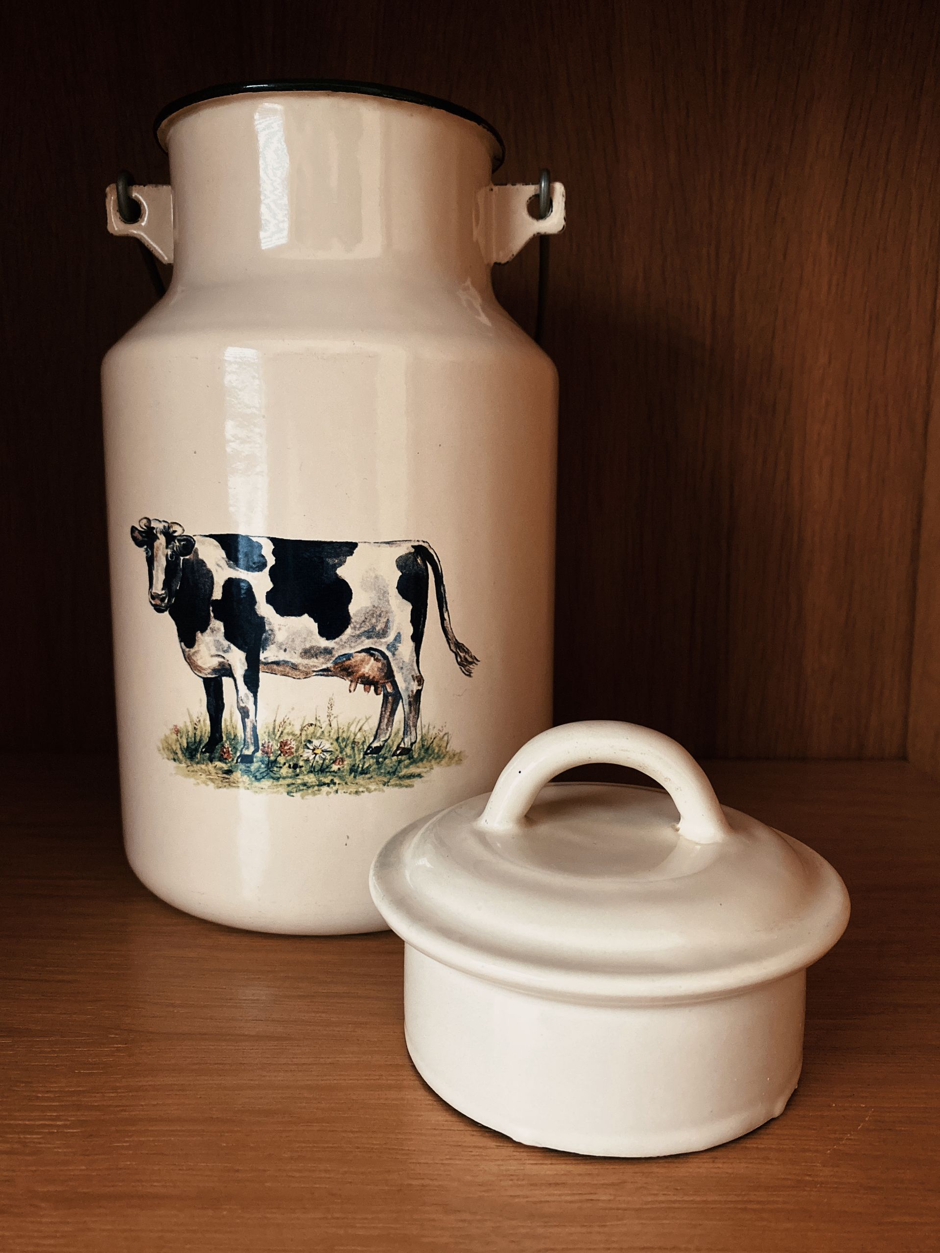Vintage geëmailleerde melkbus met een koeienafbeelding.