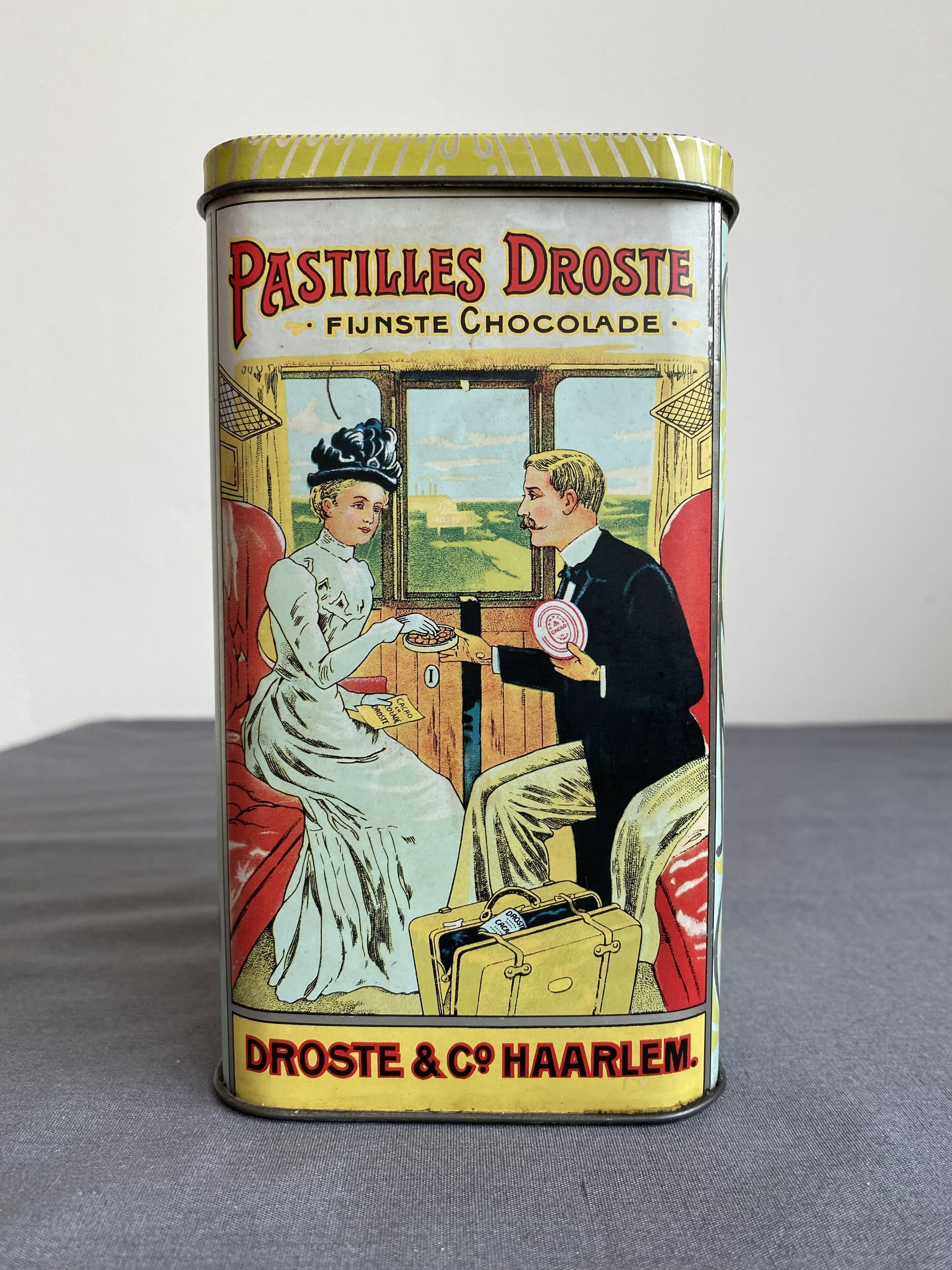 Vintage blikje Droste pastilles, met een afbeelding van een stel in een treincoupé.