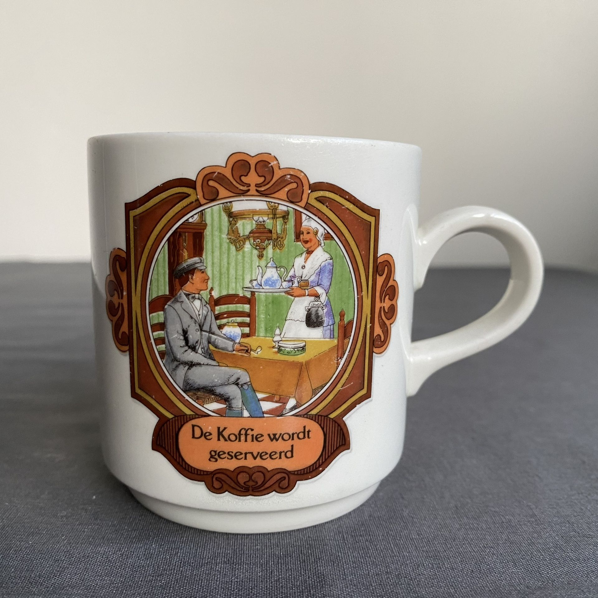 Koffiemok met afbeelding van een ober die koffie brengt naar een man die aan een tafel zit. Tekst: 