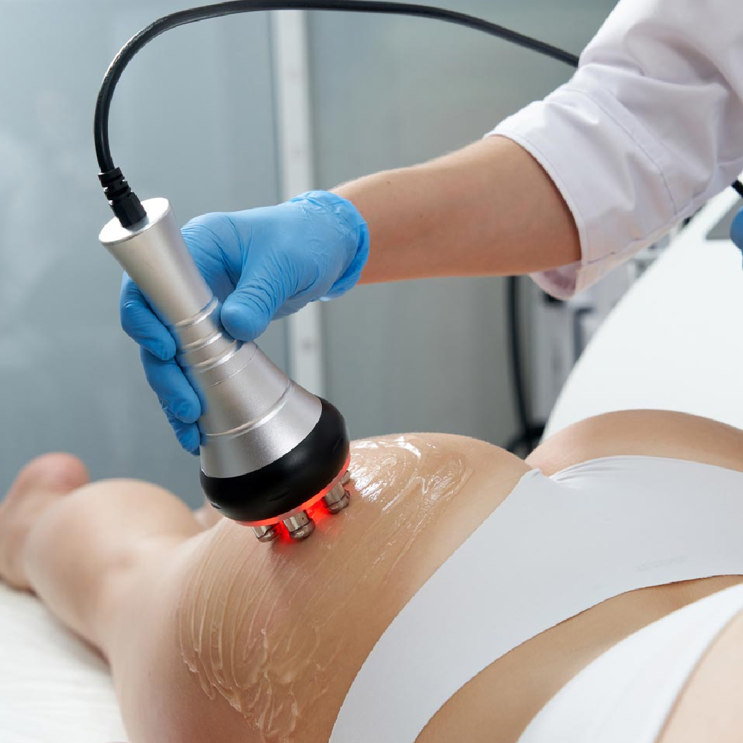Gloved clinician using a handheld device on a patient’s lower back during a body treatment