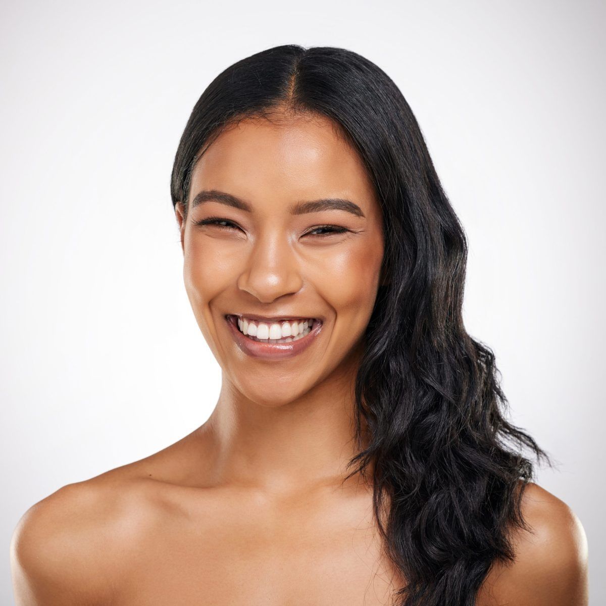 Smiling woman with long dark hair against a white background
