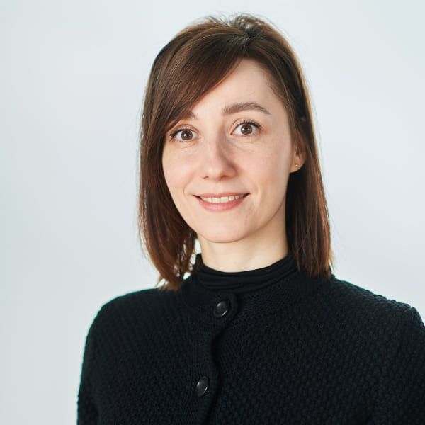 The woman is wearing a black sweater and smiling for the camera.