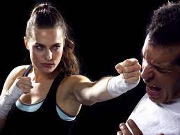 Woman in boxing pose throws a punch at a man's face.
