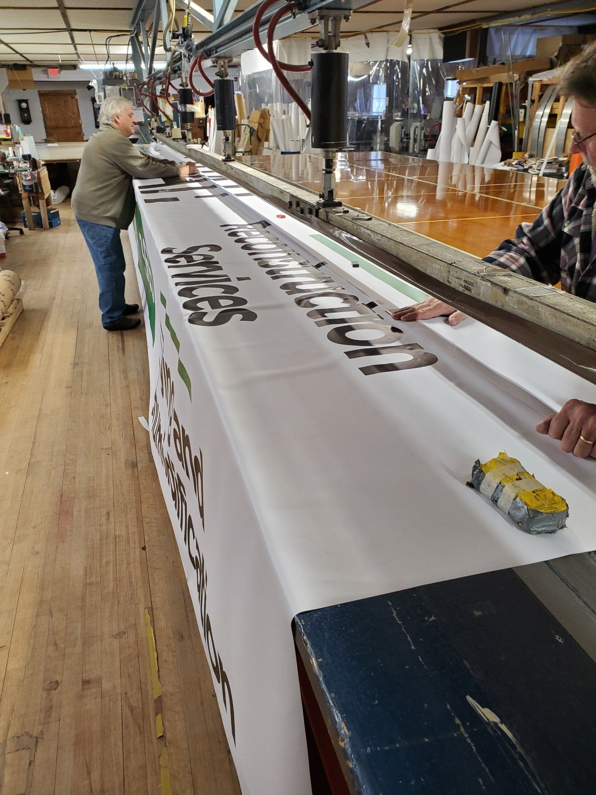A man is standing next to a machine that is making a sign