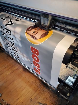 A large banner is being printed on a large printer