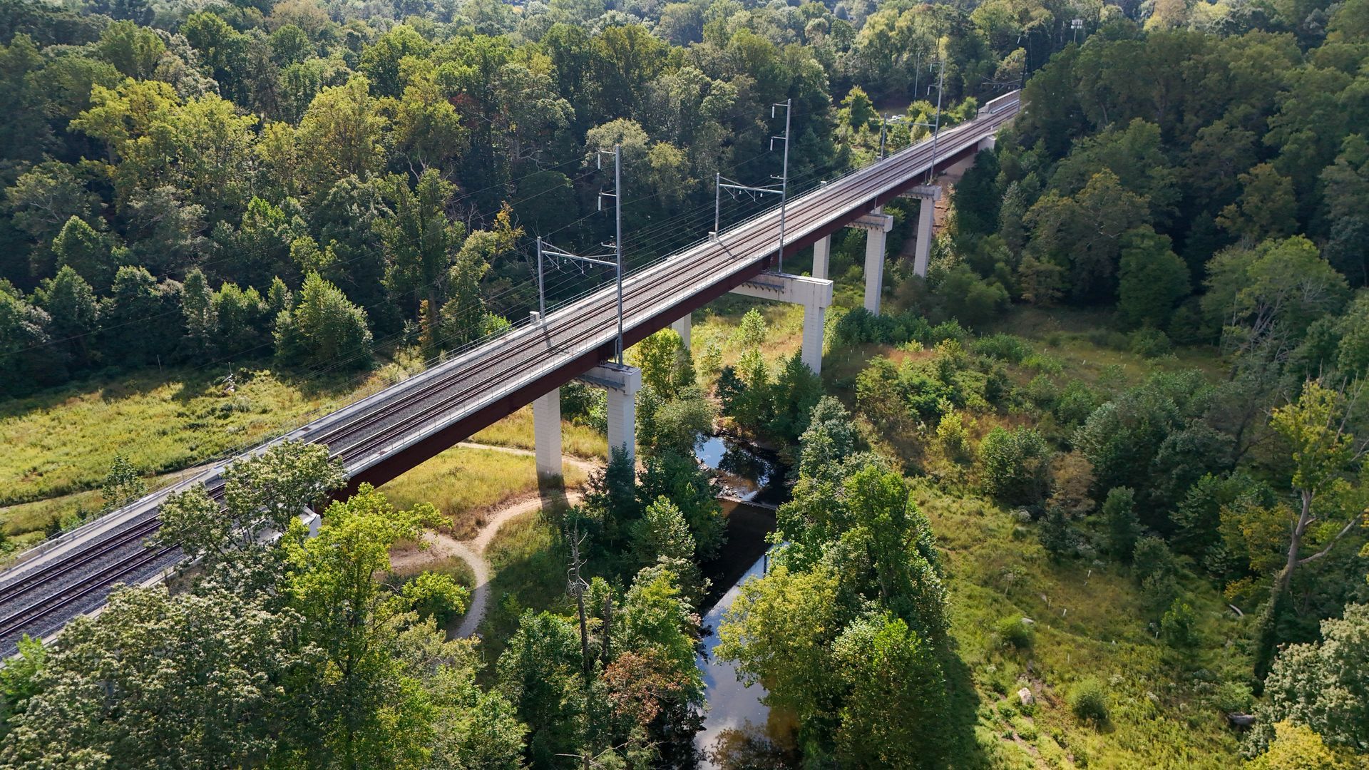 Elevated railway bridge crossing a green forested valley over a small river