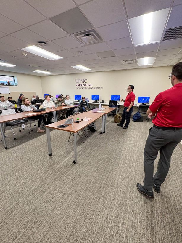 Meeting room with people seated at tables and two presenters from Blue Sky Strategic Partners in red shirts near blue monitors