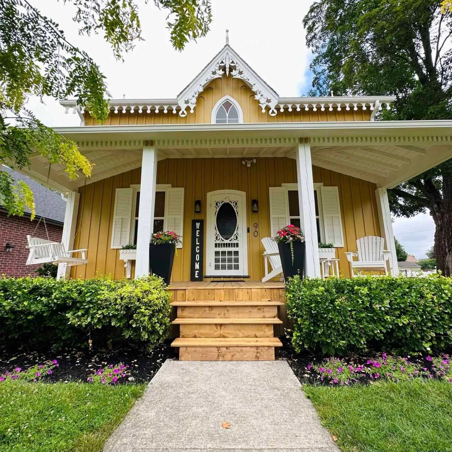 Yellow Victorian house with a porch, shutters, and a