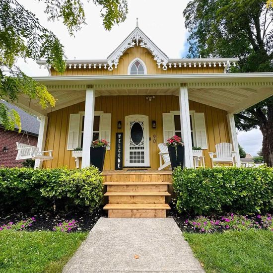 Yellow Victorian house with a porch, shutters, and a