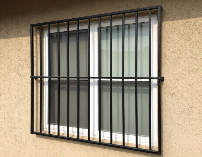 Black security bars on a window in a beige stucco wall.