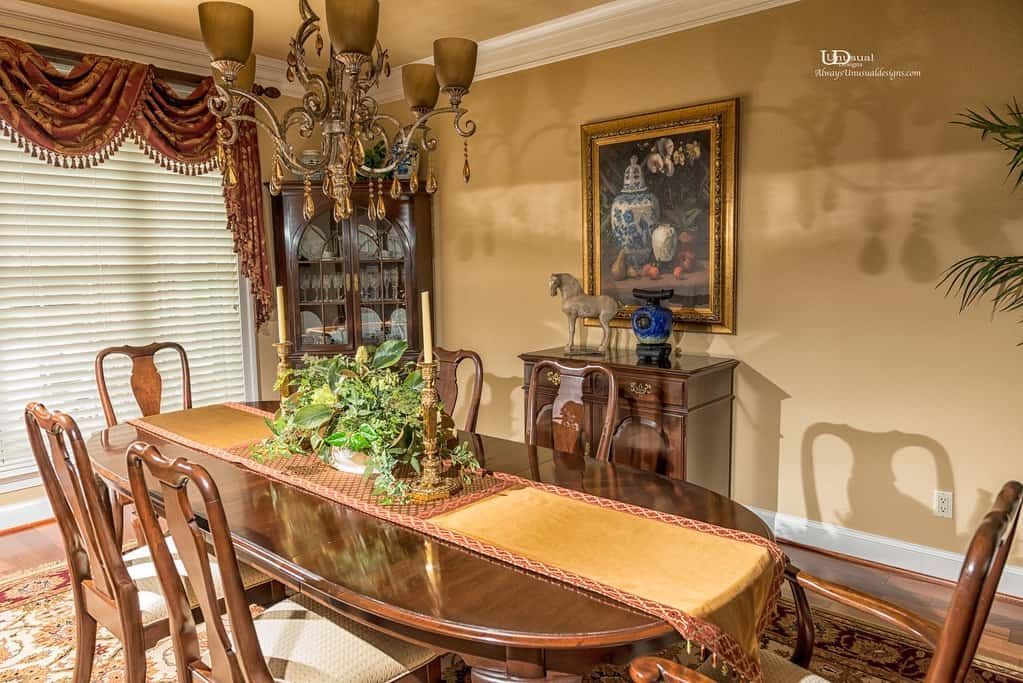 Formal dining room with long wooden table, chandelier, and china cabinet.