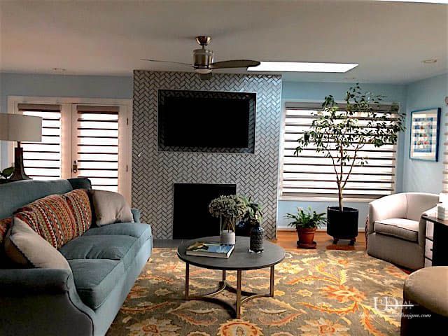 Living room with a blue sofa, gray rug, and a television above a fireplace.