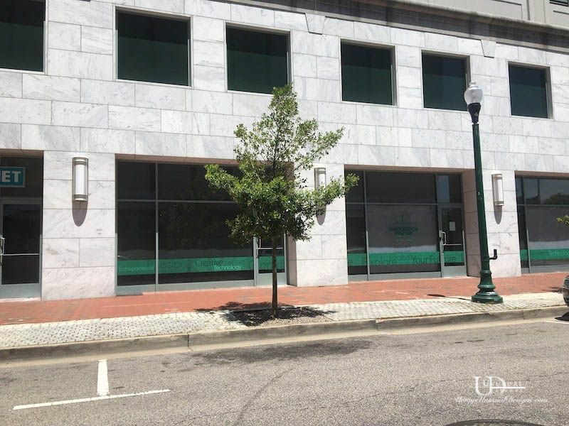 Exterior of building with windows, tree, and street. Building has gray marble facade.