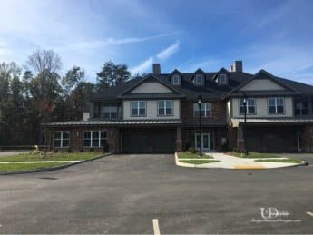 Multi-story brick building with two garages, light-colored trim, and dormers under a blue sky.