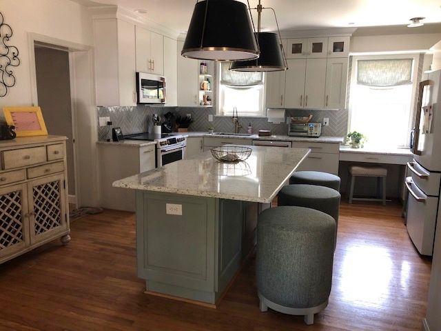 Kitchen with gray and white cabinets, island with green base and stools, hardwood floor.
