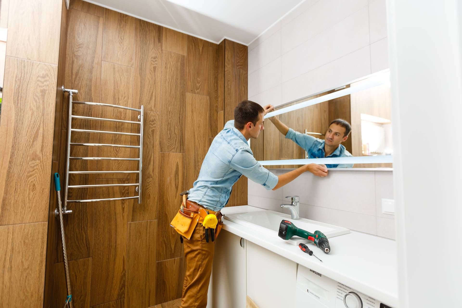 Bathroom in the middle of a design and remodeling work with a professional installing a mirror