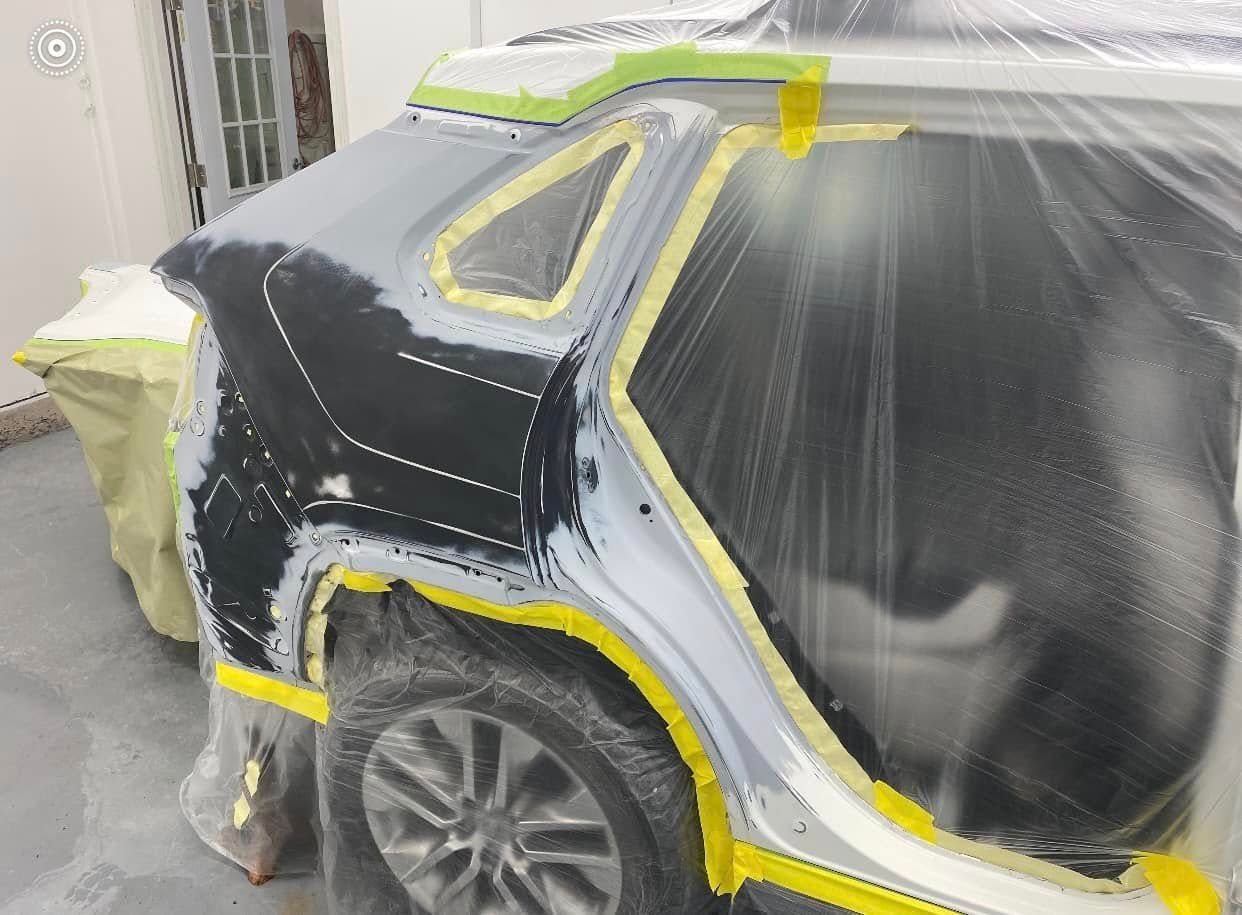 A car is being painted in a garage.