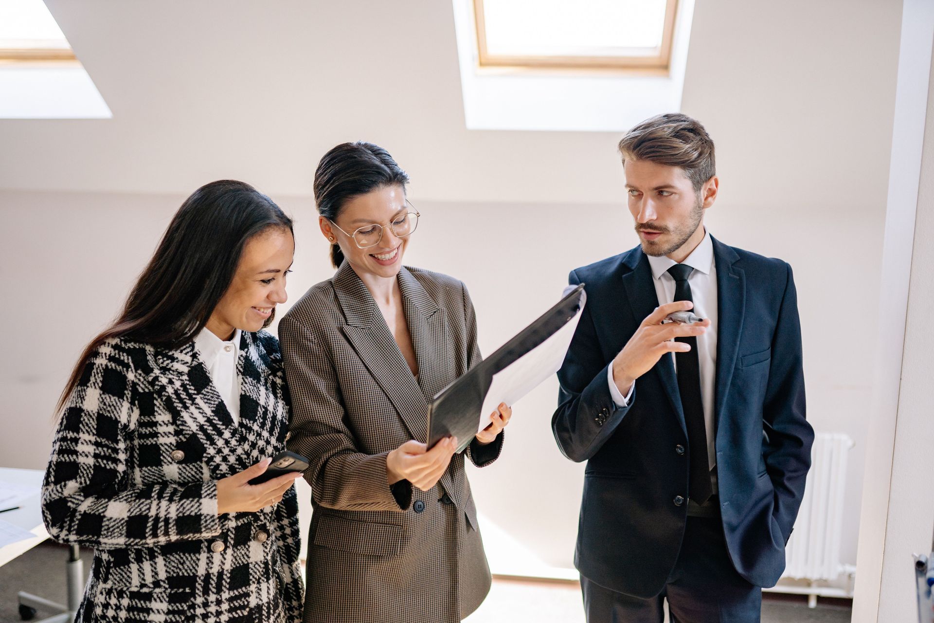Drie professionals bekijken samen een document in een lichte kantoorgang.