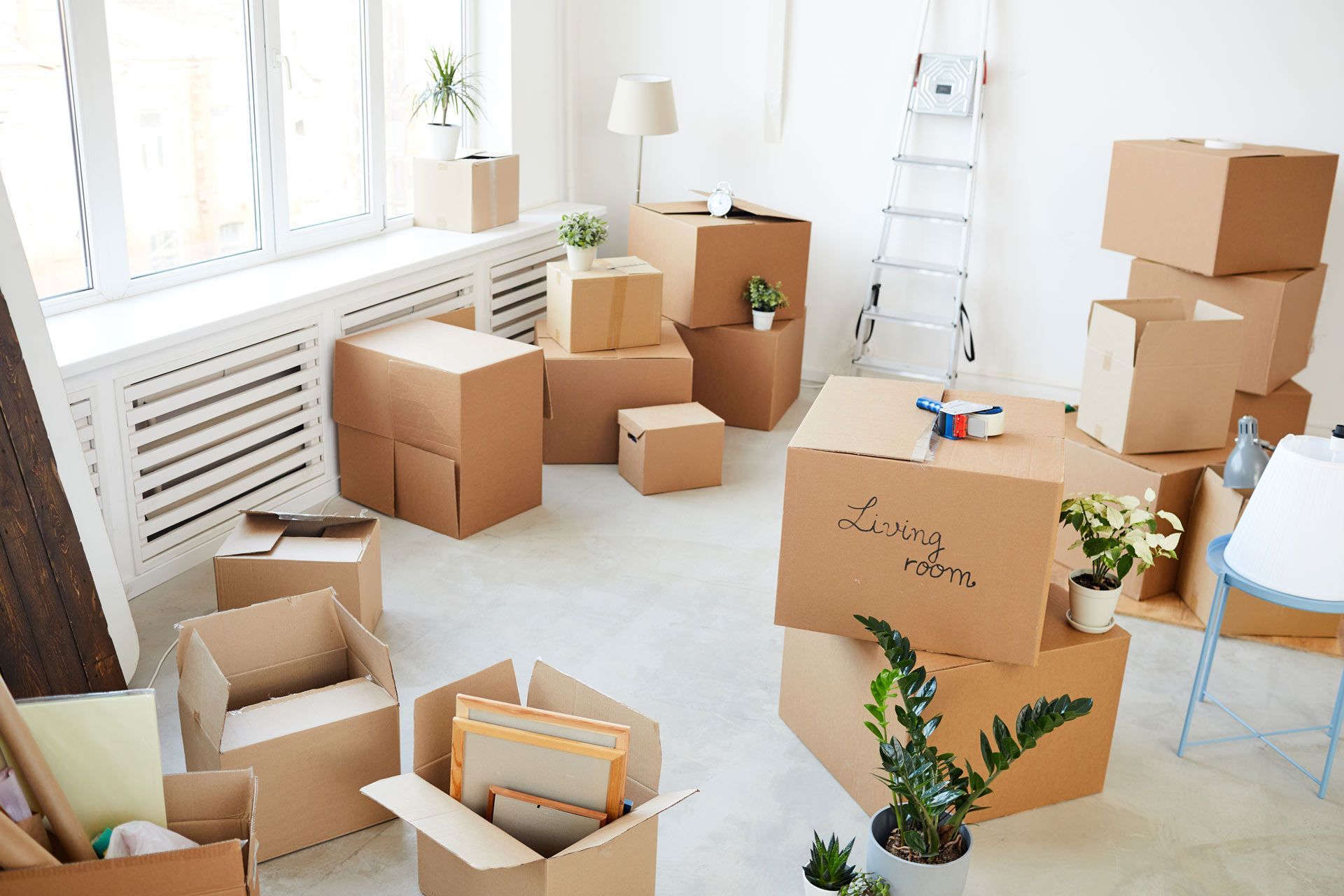 Room filled with cardboard boxes, indicating a move. Boxes stacked, unpacked, and open.