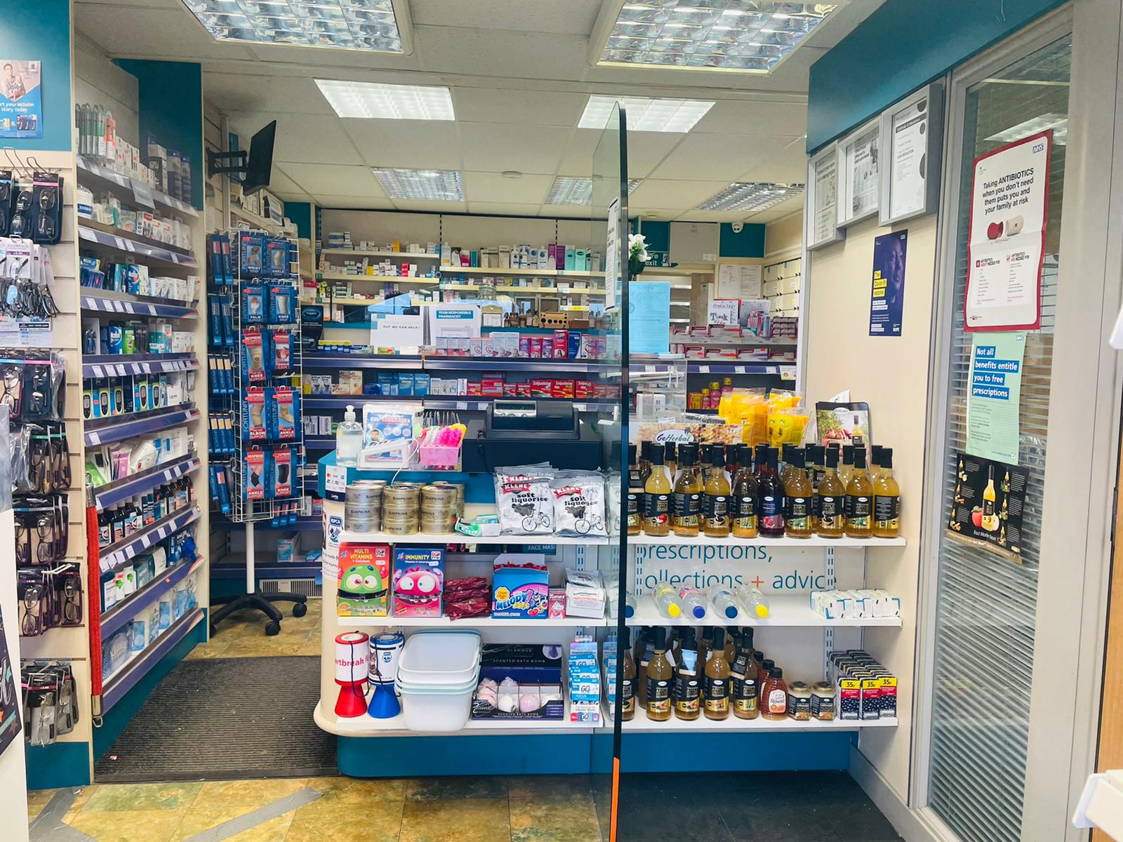Pharmacy interior showing aisles of medicines and health products, illustrating prescription collection and delivery services