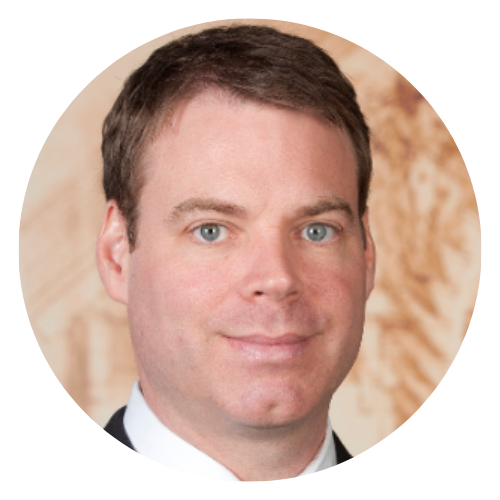 Studio headshot of a man in a suit against a beige background