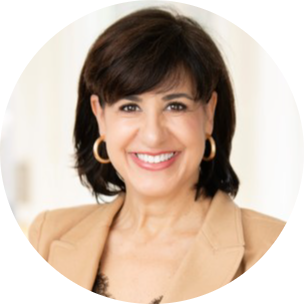Smiling woman in a beige blazer with hoop earrings, against a light background.