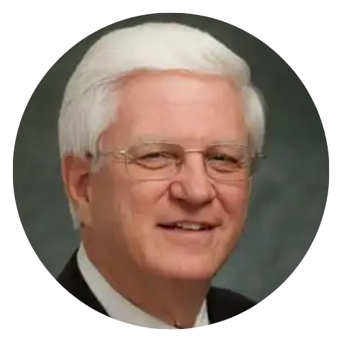 Portrait of a man wearing glasses and a dark suit against a light background