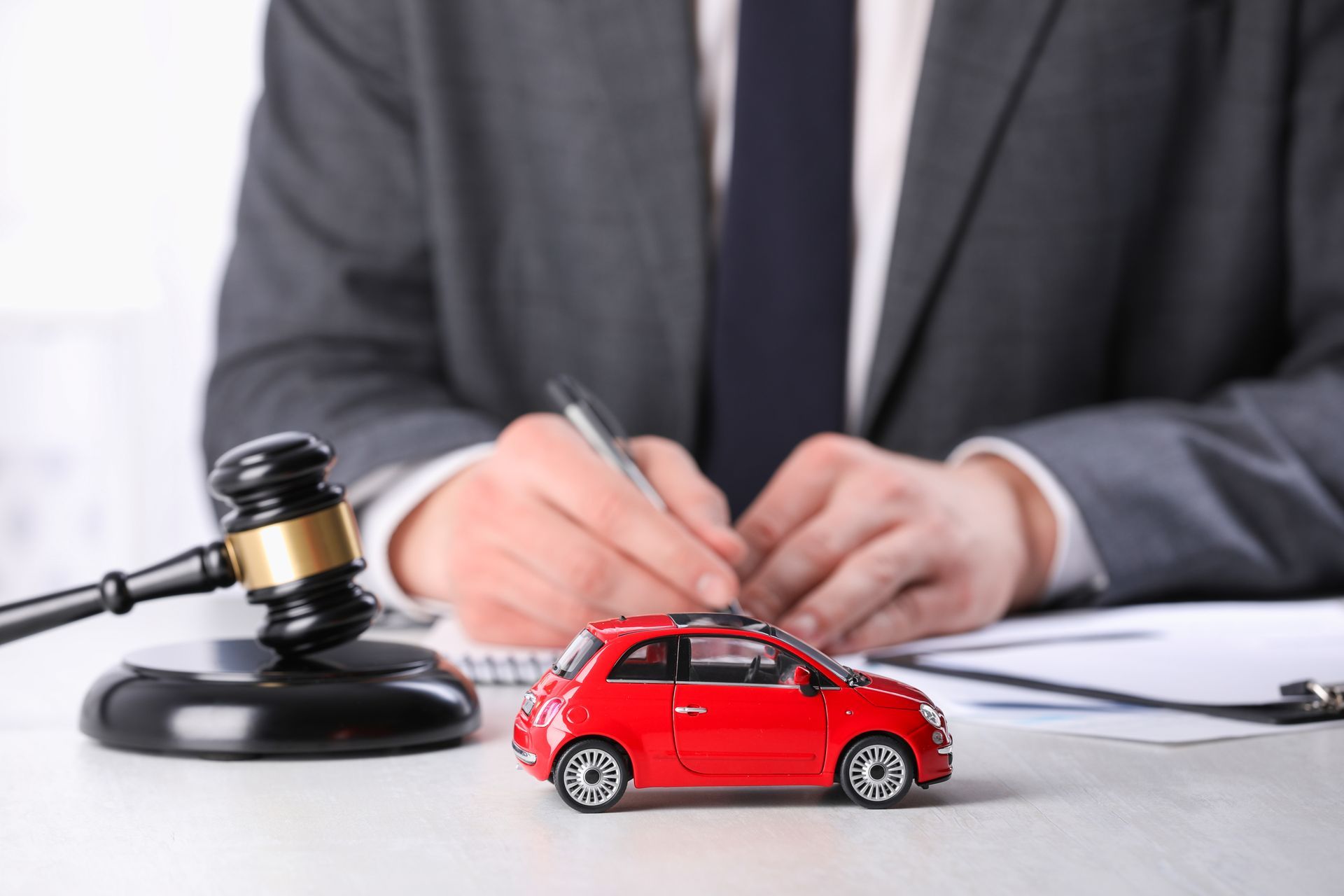 Gavel and car model beside an attorney signing traffic legal documents. Gavel and car model beside an attorney signing traffic legal documents.