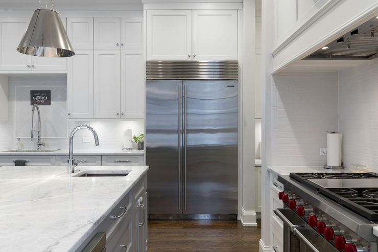 Modern white kitchen with stainless steel appliances and red stove knobs