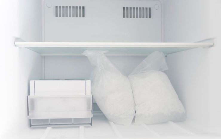 Empty white refrigerator shelf with a few ice packs and a plastic container inside