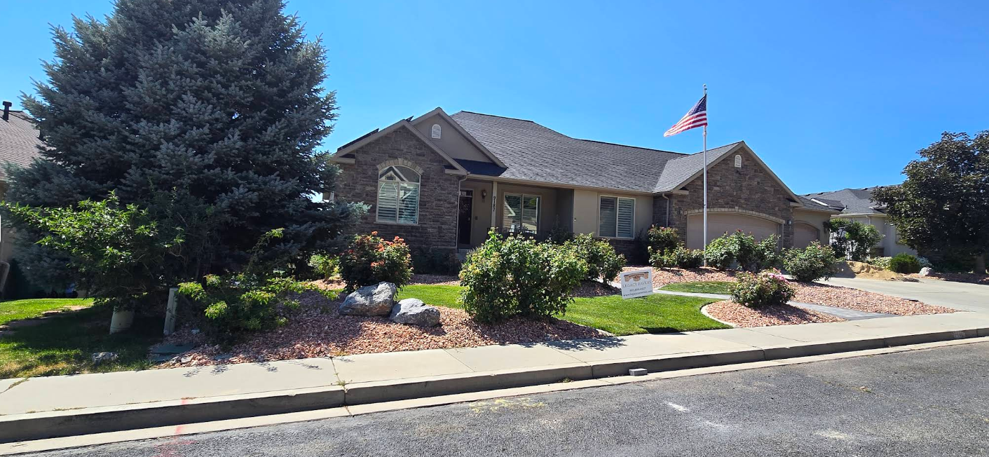 Single-story brick house with a front yard, shrubs, and an American flag by the curb