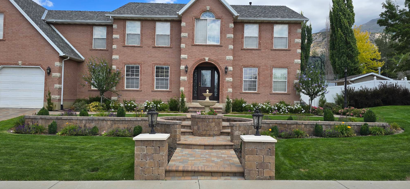 Brick apartment building with central stone steps, green lawn, and landscaped front garden