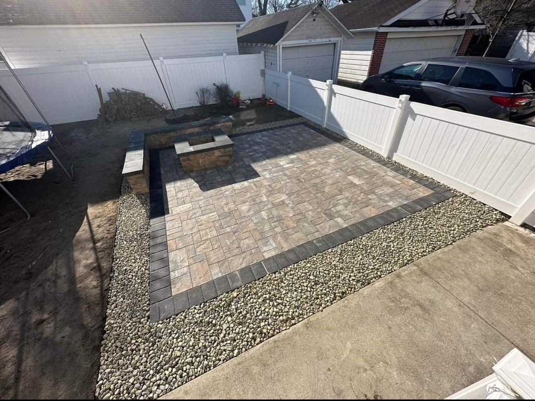 A white fence surrounds a patio area in a backyard.