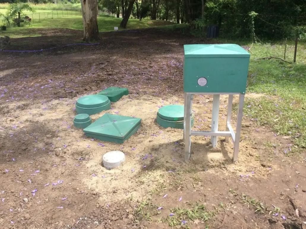 A Green Box Is Sitting in The Middle of A Dirt Field — Murwillumbah District Plumbing Service in Uki, NSW