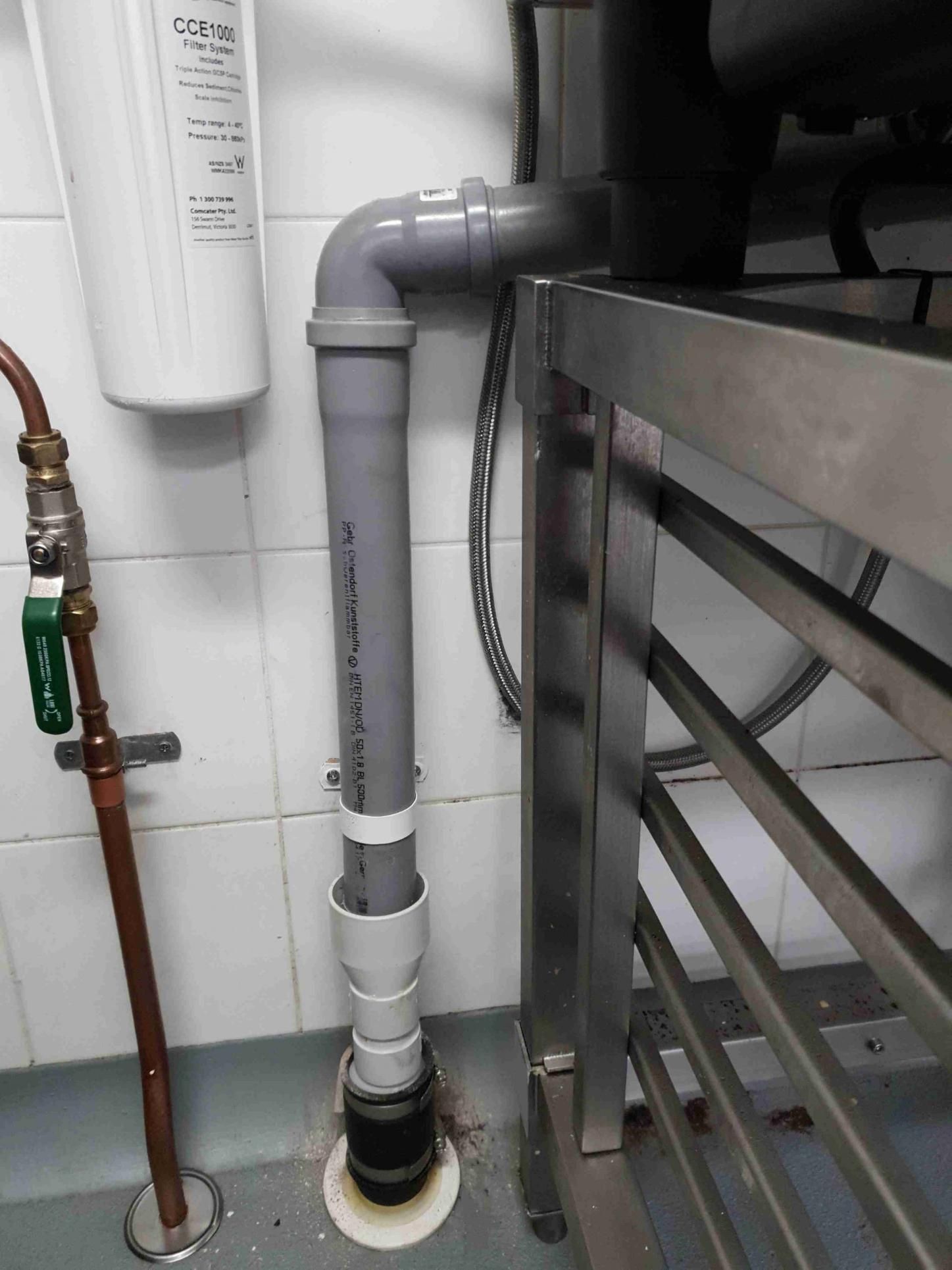 A Pipe Is Connected to A Water Filter in A Kitchen — Murwillumbah District Plumbing Service in Nunderi, NSW