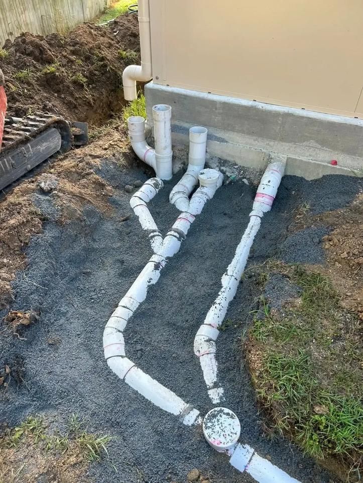 A Bunch of White Pipes Are Laying on The Ground Next to A House — Murwillumbah District Plumbing Service in Nunderi, NSW
