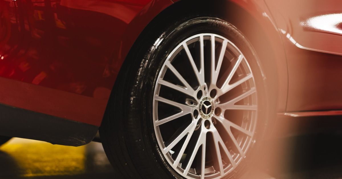 A close-up of a red car wheel and tire with a silver rim, glossy paint, and warm light reflections.