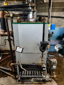 Industrial boiler or tank with pipes, gauges, and wiring in a mechanical room