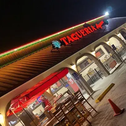 A taqueria restaurant with tables and chairs outside at night