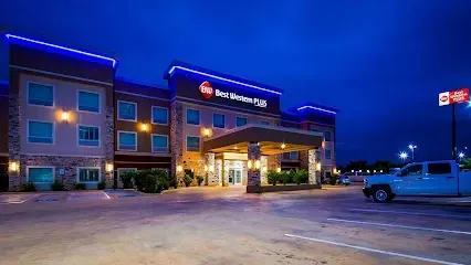 A white truck is parked in front of a hotel at night.