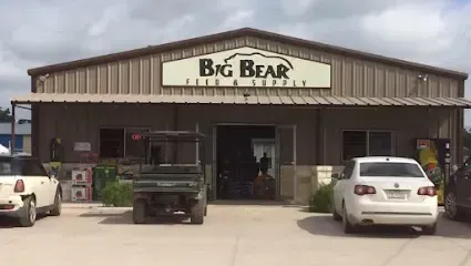 Two cars are parked in front of a big bear store.