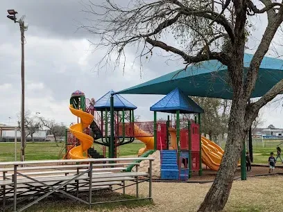 A playground with a slide and bleachers in a park.