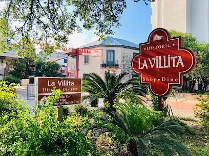A sign for la villita shop and dine is in front of a building.