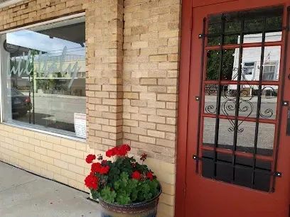 A brick building with a red door and a potted plant in front of it.