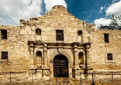 A large stone building with a doorway and a blue sky in the background.