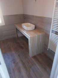 Bagno moderno con mobiletto in legno e lavabo a ciotola bianco, pareti piastrellate in grigio e pavimento in legno scuro.