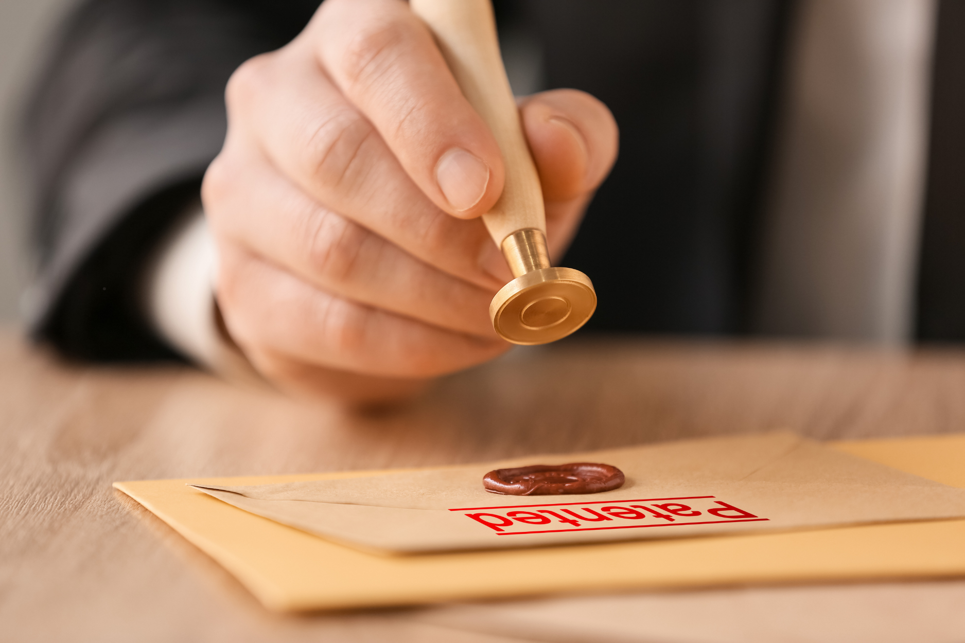 A man is stamping an envelope with a wax seal.